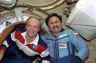 STS-91 Commander Charlie Precourt and Mir-25 cosmonaut Talgat Musabayev greet one another at the Docking Module hatch. 